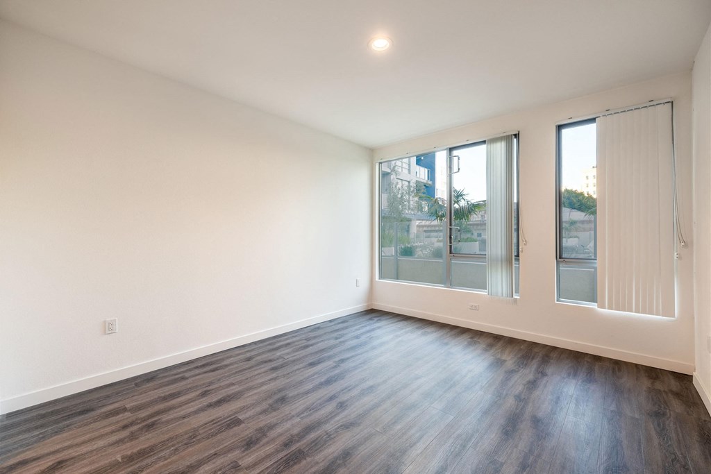 a living room with white walls and wood floors and a large window