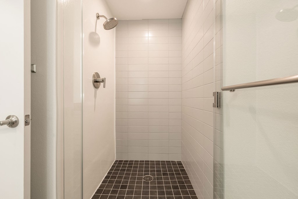 a tiled shower in a bathroom with a white door