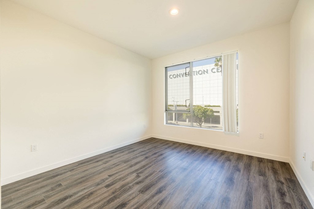 an empty living room with wood flooring and a window