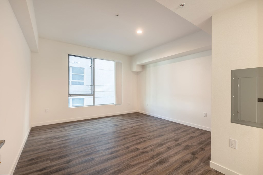 an empty living room with wood flooring and a window