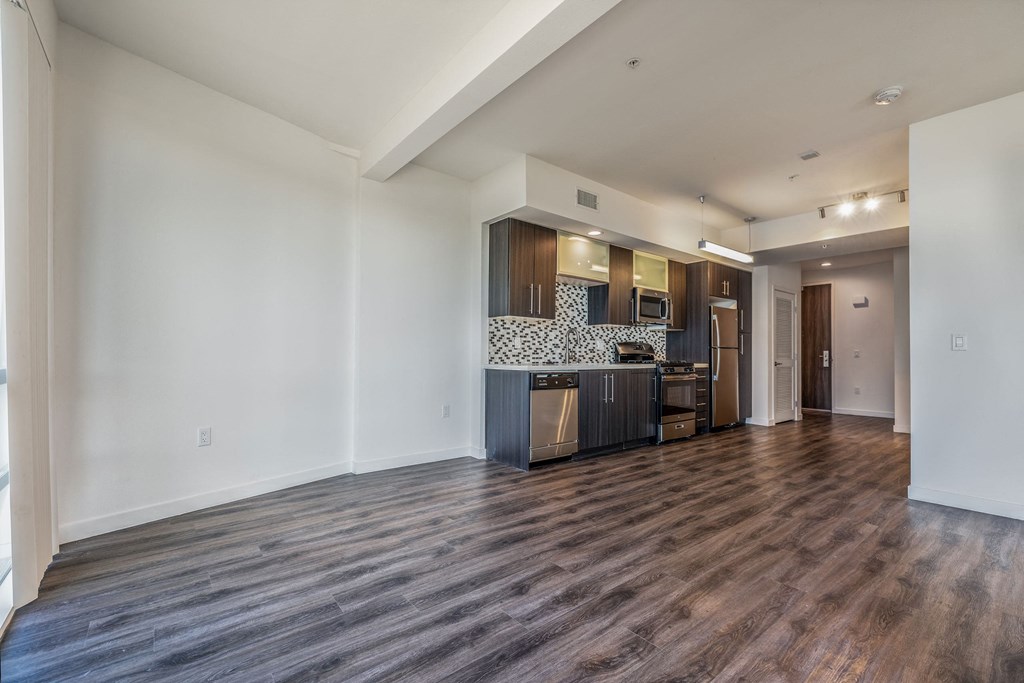 a living room and kitchen with a wood floor and white walls
