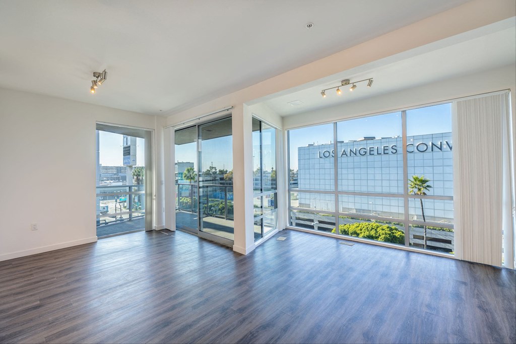 a living room with wood flooring and large windows and a balcony
