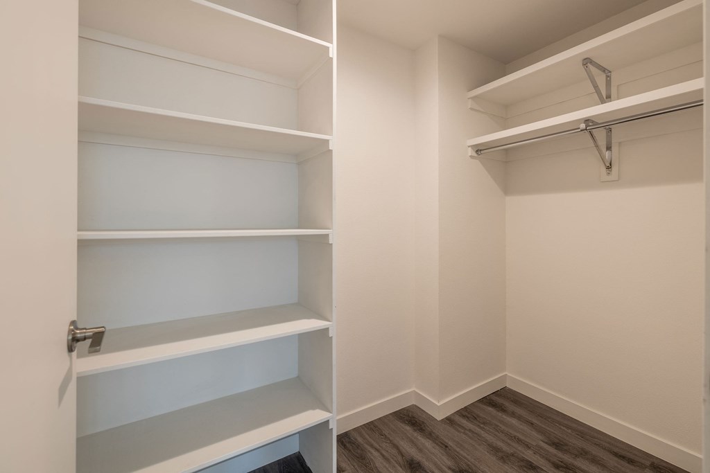 a walk in closet in a home with empty shelves