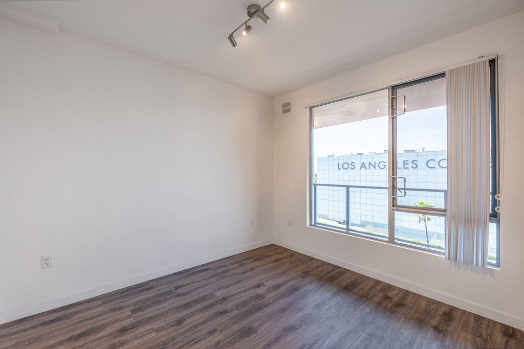 an empty living room with a large window and wood flooring