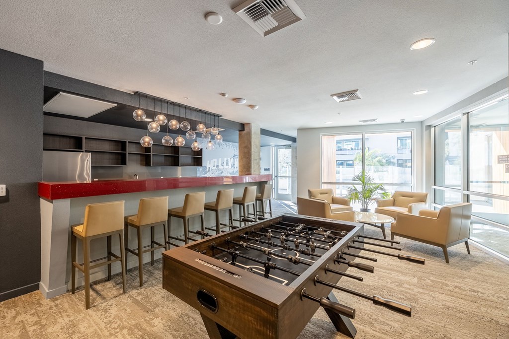 a clubhouse with a foosball table and a bar with chairs