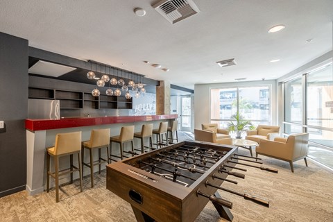 a clubhouse with a foosball table and a bar with chairs