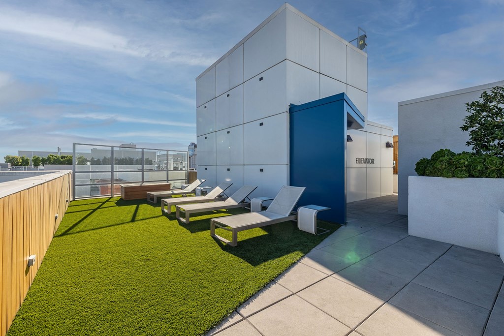 a rooftop terrace with lounge chairs and a building in the background