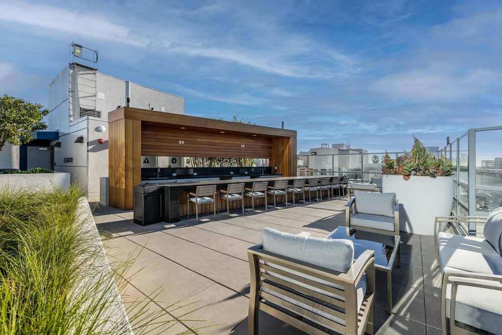 a rooftop patio with a bar and chairs and furniture