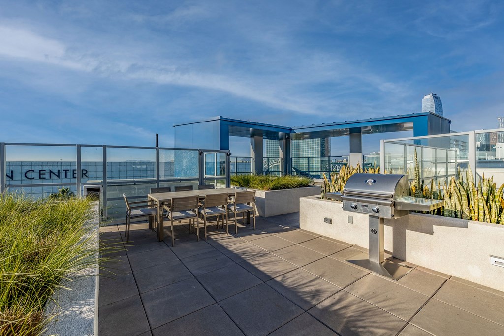 a patio with a barbecue grill and tables on a roof