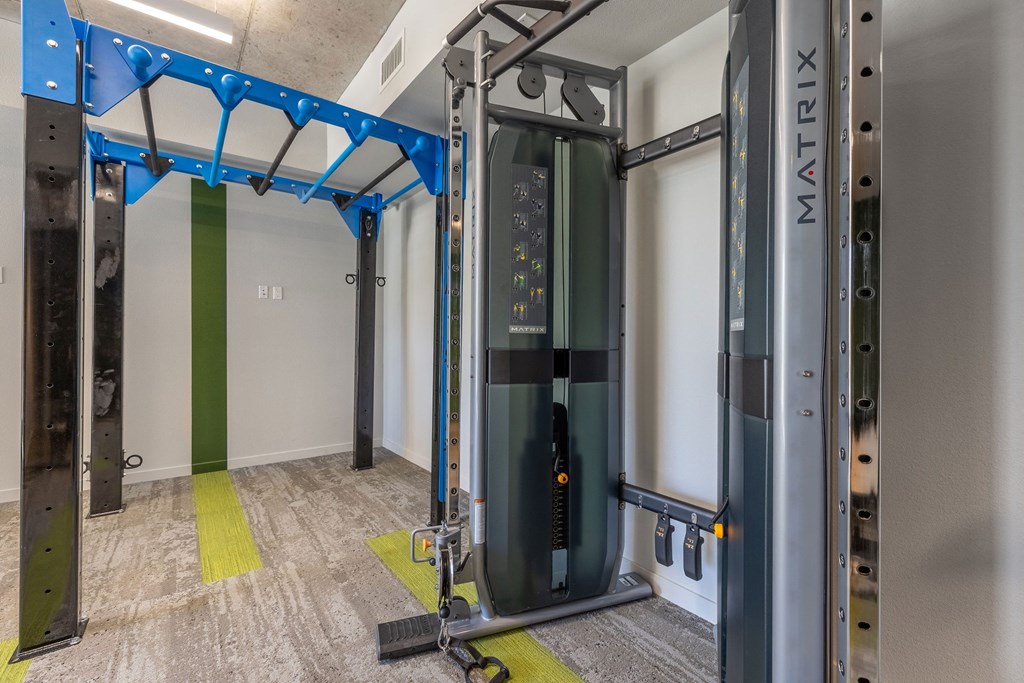 a fitness room with a treadmill and weights in the corner of a room