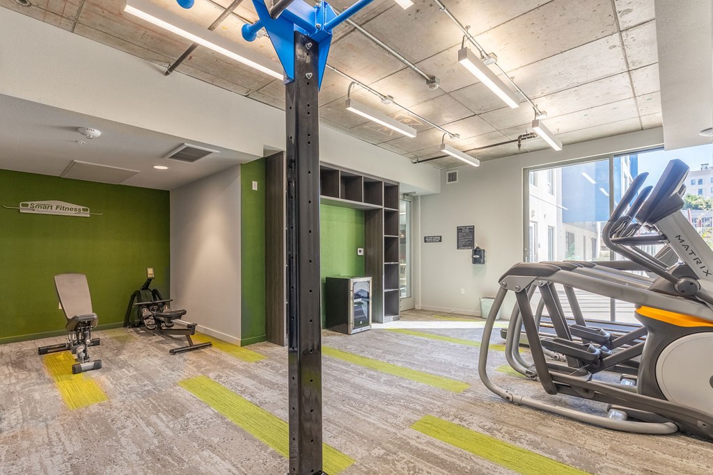 a gym with cardio equipment and green walls and a large window