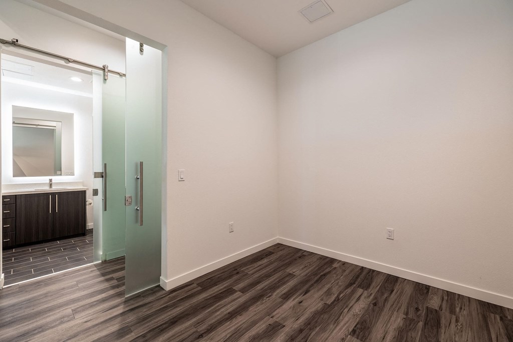 Spacious bedroom with hardwood flooring and high ceilings in a Live and Work apartment at 1400 FIG Apartments in Los Angeles, California.
