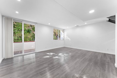 A spacious room with wooden flooring and sliding glass doors.
