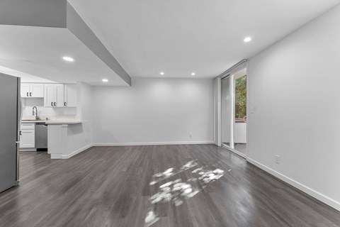 A kitchen with a refrigerator, sink, and cabinets is visible from the living room.