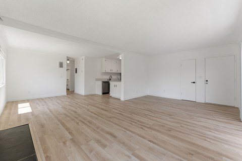 A spacious room with wooden flooring and white walls.