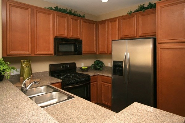 Beautiful and spacious kitchen cabinets, granite slab countertops, and large refrigerator at Serenata Townhomes in San Diego, California.