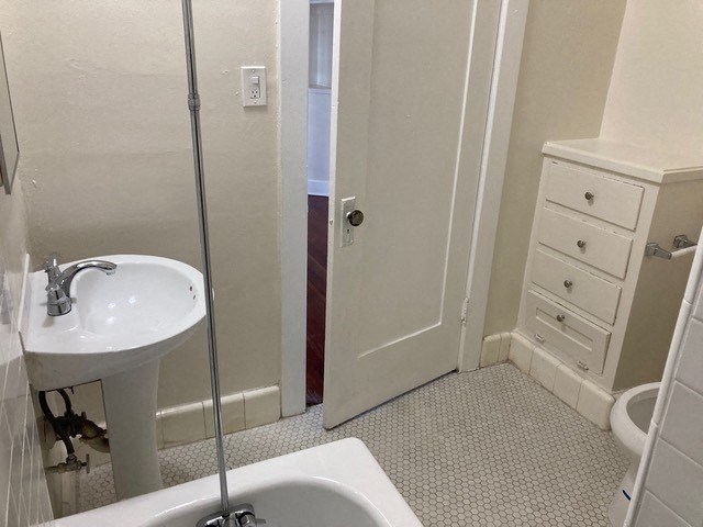 Bathroom with built-in dresser, white fixtures and old-style charm at The Western at Rosewood Apartments in Los Angeles, California.