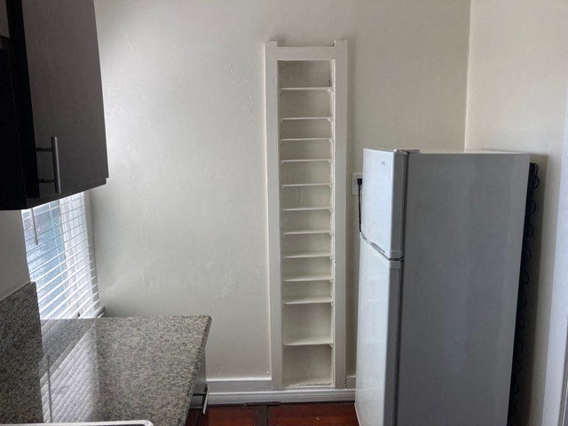 Old-style storage and modern appliances in kitchen with hardwood floor and dark wood cabinets at The Western at Rosewood in Los Angeles, California.