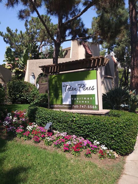 Enterance monument sign surrounded by beautiful gardens at Teton Pines Apartments in Escondido, California.