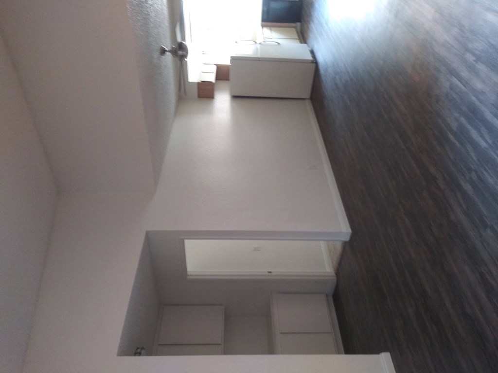 Living room view of kitchen and hallway to bedrooms with built-in cabinets at La Costa Seashore Apartments.