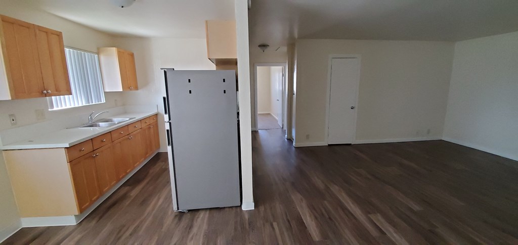 Looking down hallway to bedrooms and kitchen with wood stained cabinets and window at Zenith Place Apartments in Chula Vista, California.