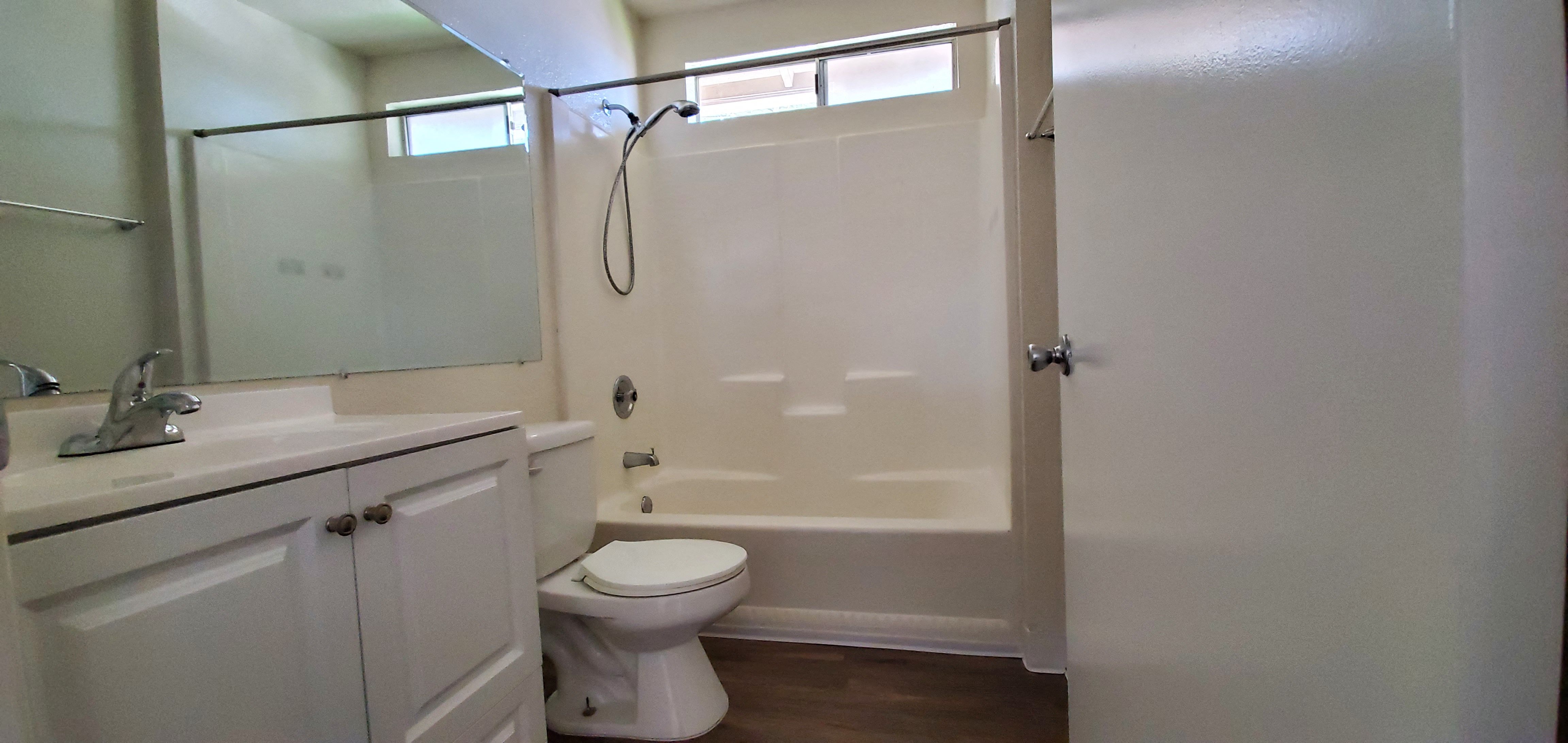 White bathroom with hardwood floor and natural light at Zenith Place Apartments in Chula Vista, California.