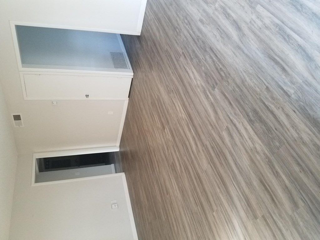 Living room with hardwood flooring at Tulip Street Apartments in Escondido, California.