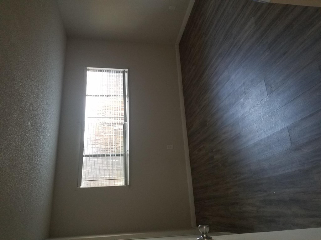 Bedroom with hardwood flooring and large window at Tulip Street Apartments in Escondido, California.