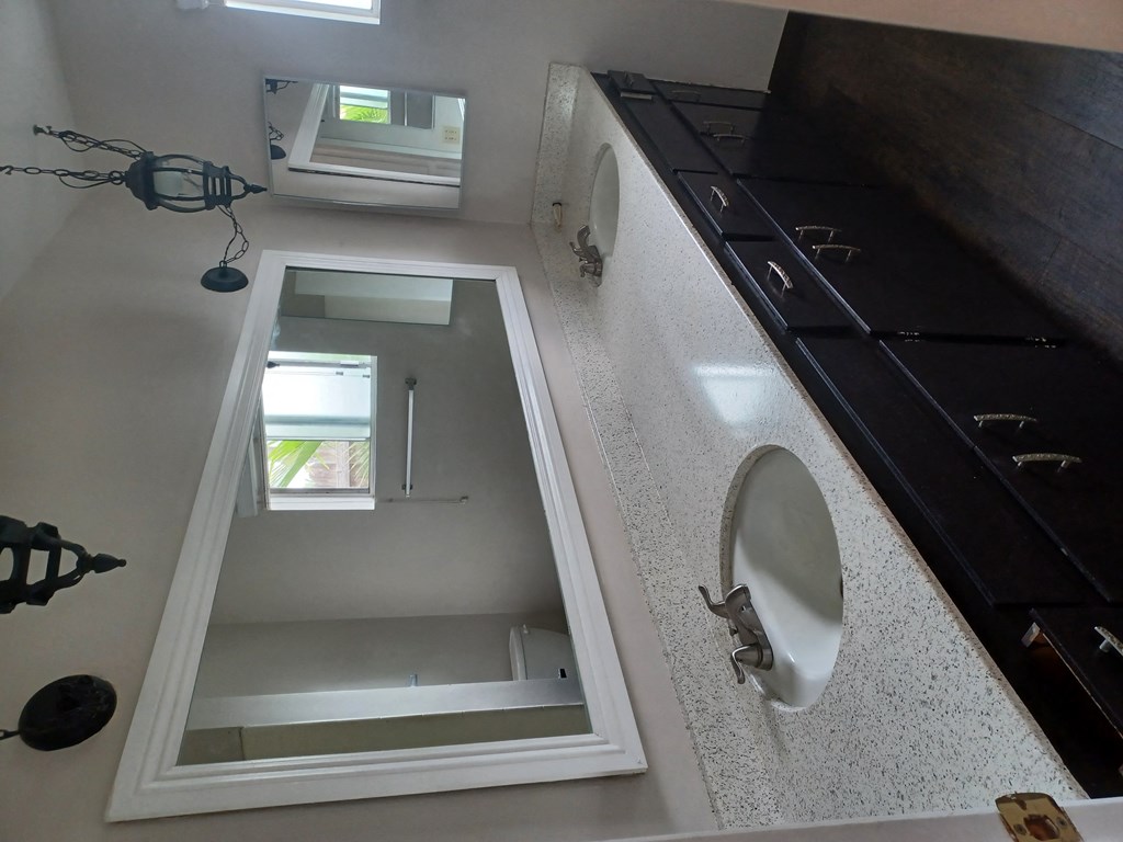 Bathroom with double vanity with lots of cabinet space and window at Juniper Street Apartments in Escondido, California.