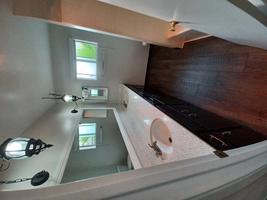 Bathroom with hardwood flooring, dark wood cabinets on double vanity and privacy window at Juniper Street Apartments in Esdondido, California.