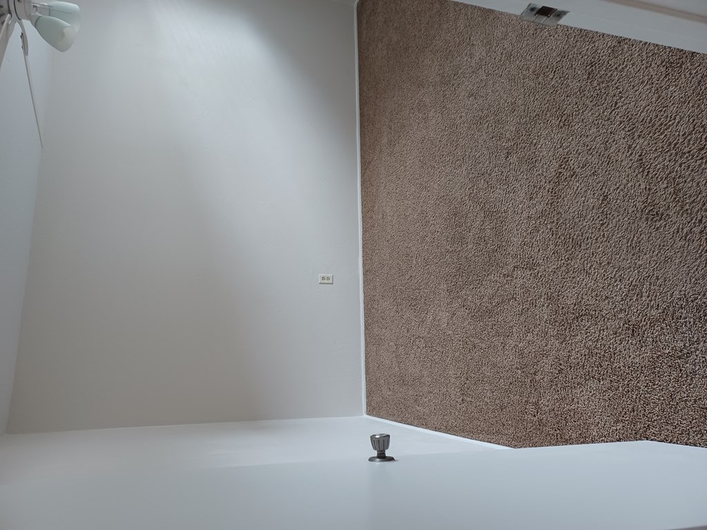 Carpeted bedroom with ceiling fan/light at Juniper Street Apartments in Escondido, California.