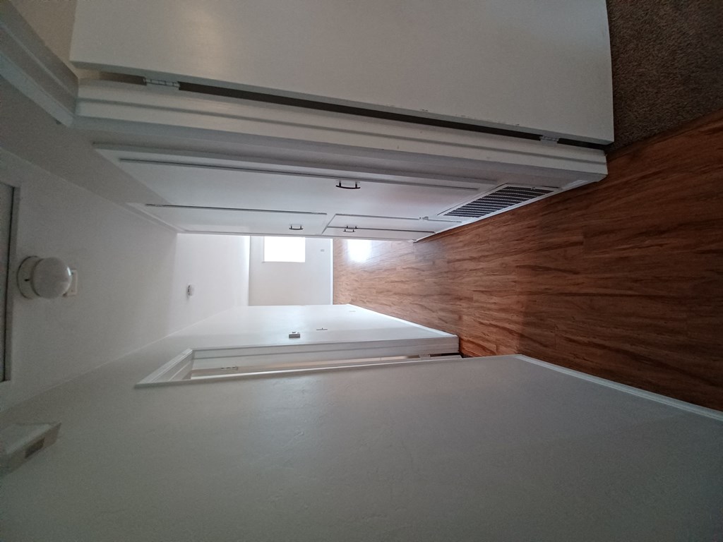 Bedroom/bathroom hallway with hardwood and lots of cabinets at Juniper Street Apartments in Escondido, California.