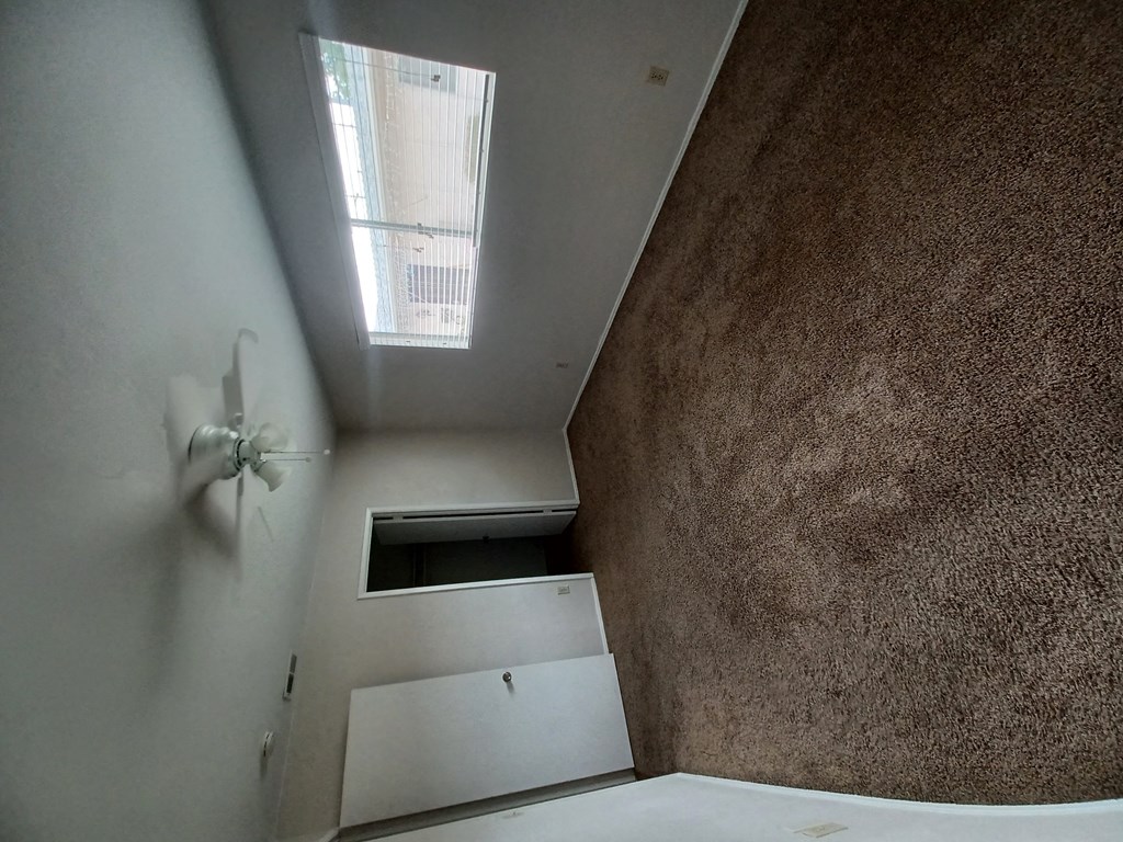Carpeted bedroom with nice double window, ceiling fan, and walk-in closet at Juniper Street Apartments in Escondido, California.