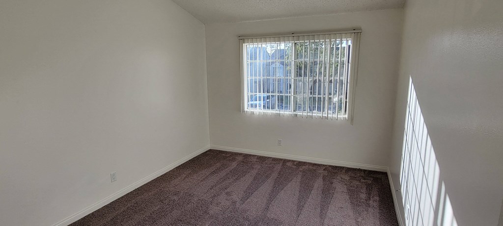 Carpeted bedroom with large window at Northwood Apartments in Upland, California.