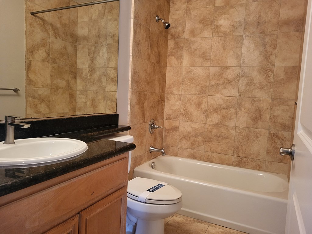 Elegant tile bathroom with white fixtures and granite counter top at The Cove at Bear Valley in Escondido, California.
