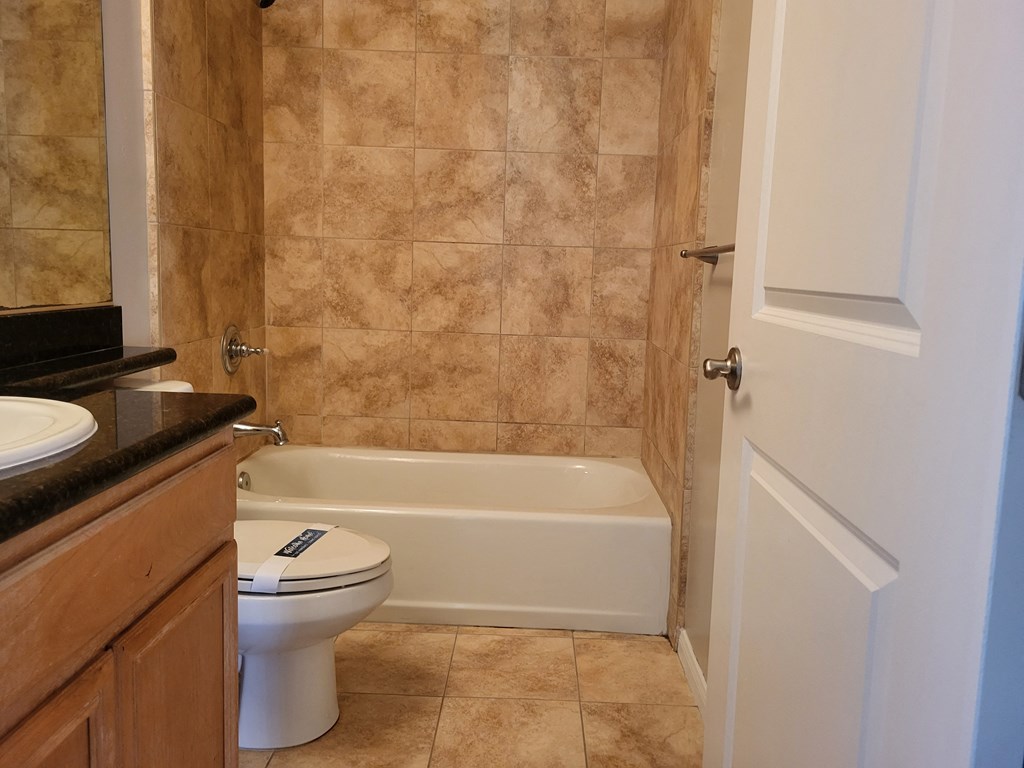 Bathroom with granite countertop and white fixtures at The Cove at Bear Valley in Escondido, California.