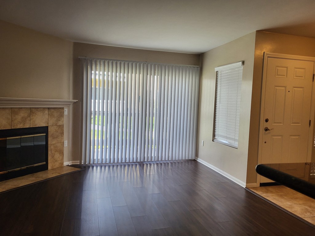 Living room with plank style flooring, beautiful fireplace and lots of windows at The Cove at Bear Valley in Escondido, California.