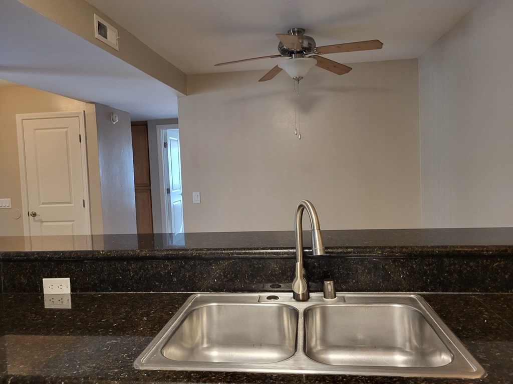 Open kitchen with lots of counter space open to dining room with ceiling fan at The Cove at Bear Valley in Escondido, California.