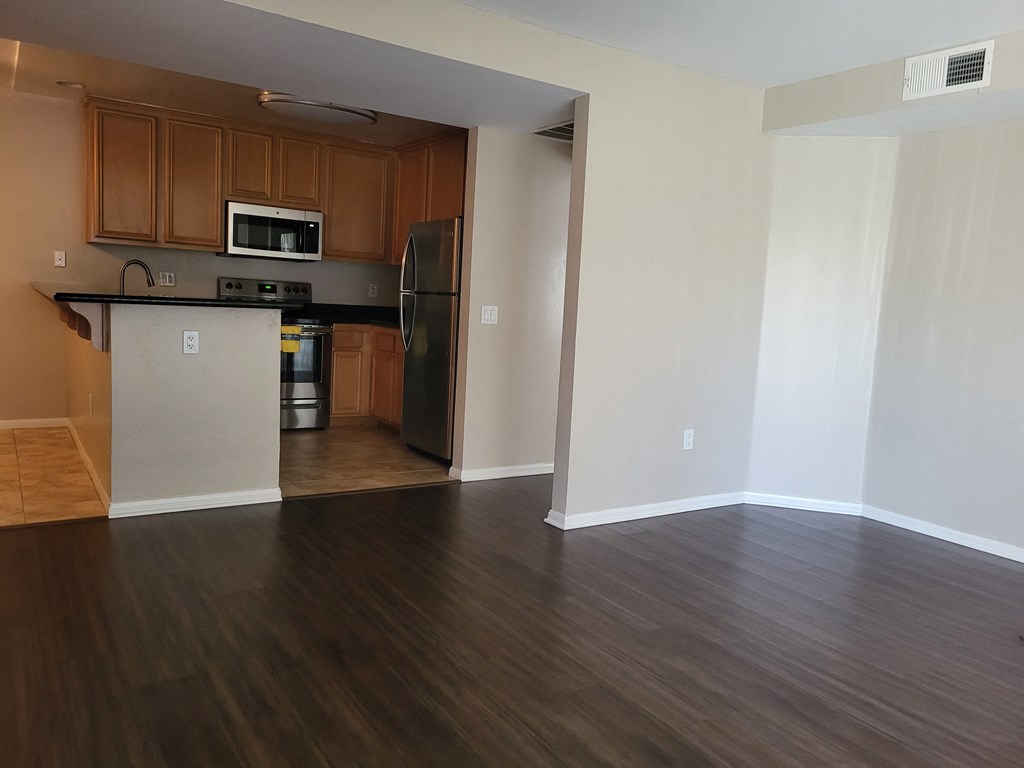 Living room looking towards kitchen with stainless steel apliances including refrigerator, stove, microwave, and dishwasher at The Cove at Bear Valley in Escondido, California.