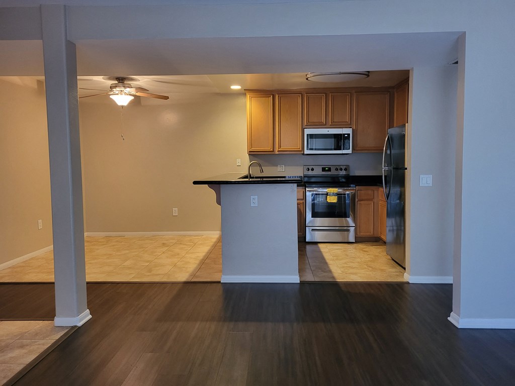 Living room view of kitchen and dining room with ceiling fan and tile floors at The Cove at Bear Valley in Escondido, California.