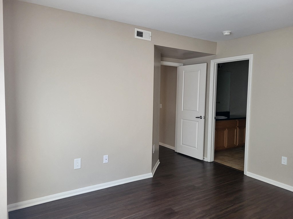 Master bedroom with plank style flooring, private bathroom and large walk-in closet at The Cove at Bear Valley in Escondido, California.