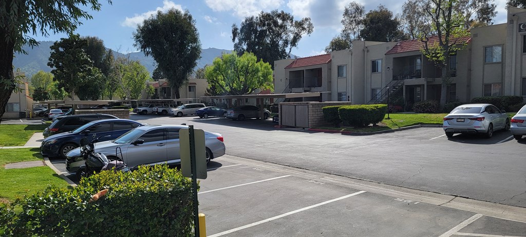 Assigned gated parking and apartment balconies in lush landscaping at Sierra Vista Apartment Homes in Lake Elsinore, California.