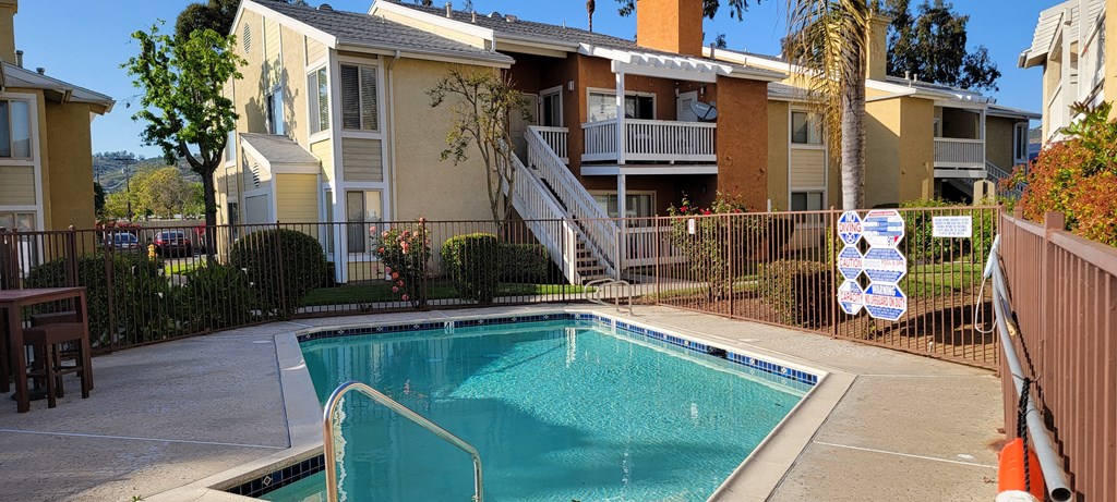 Sparkling swimming pool nestled between apartment buildings in lush garden courtyard at The Cove at Bear Valley in Escondido, California.