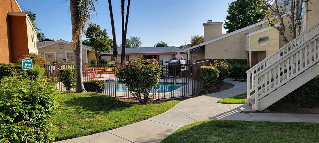 Swimming pool and spa area  with beautiful gardens and view of garages in background at The Cove at Bear Valley in Escondido, California.