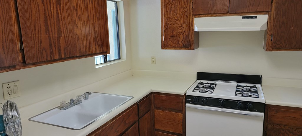 Kitchen with gas stove and spacious wood stained cabinets at Magnolia Apartments in Riverside, California.