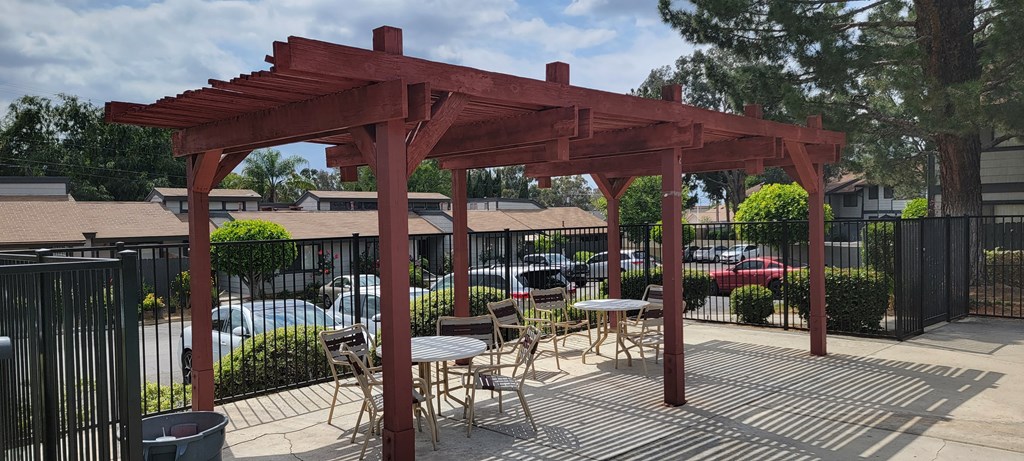 Sun deck with a wooden pergola, tables, and chairs around the pool area.