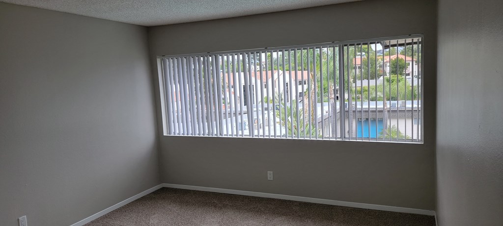 Carpeted bedroom with fantastic window and walk-in closet at La Mesa Village Apartments in La Mesa, California.
