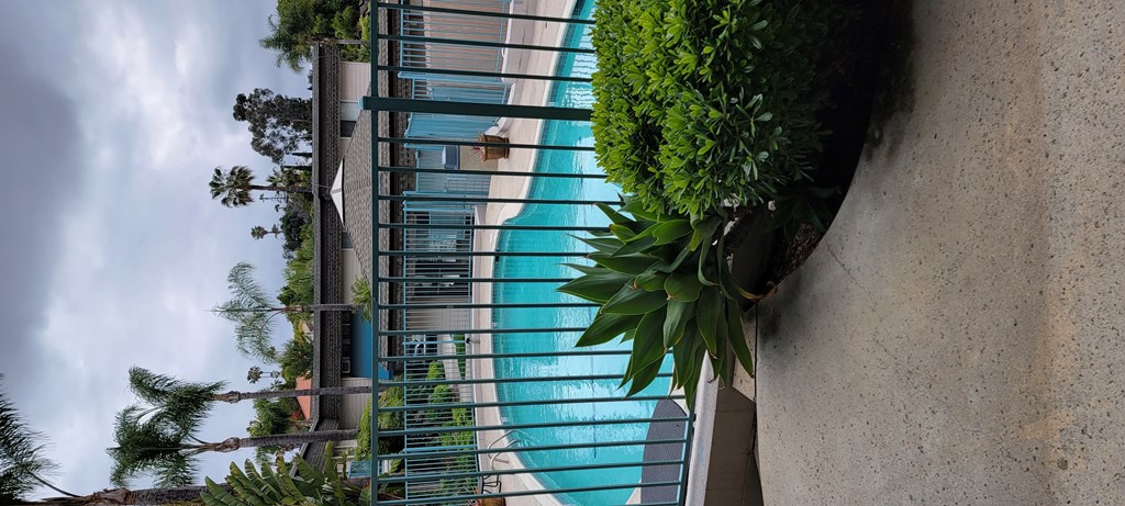 View from back building entry towards front of complex with swimming pool, leasing office and front buildings in background at La Mesa Village Apartments in La Mesa, California.