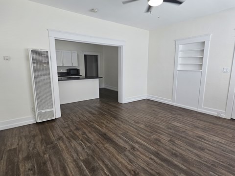 A room with a ceiling fan and wooden flooring.