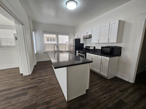A kitchen with white cabinets and a black countertop.